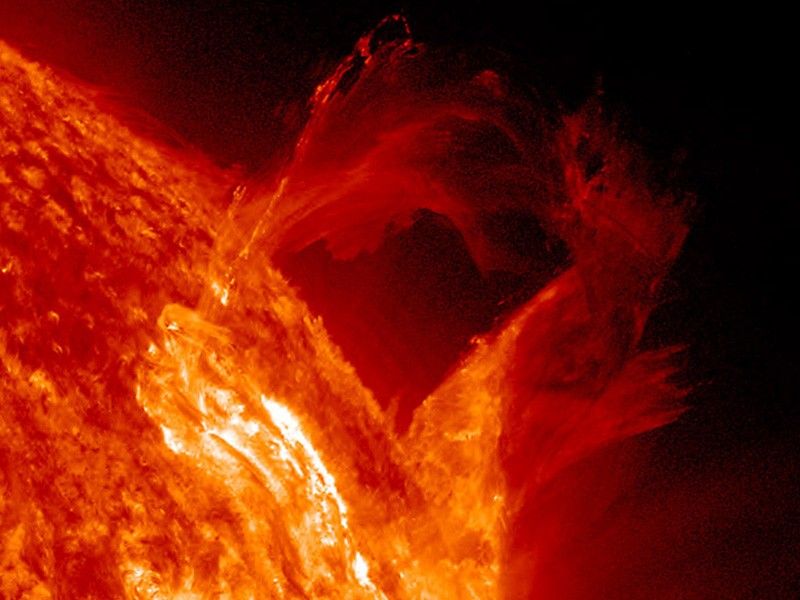 A bright loop of solar plasma rises above the edge of the Sun.